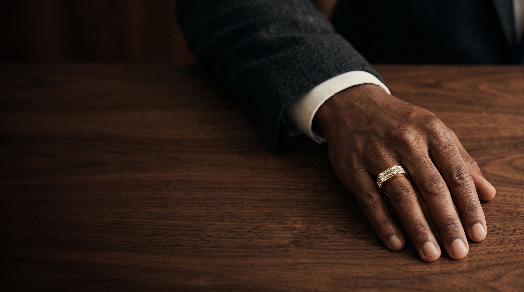A Noor five-baguette band in gold, worn on a walnut desk